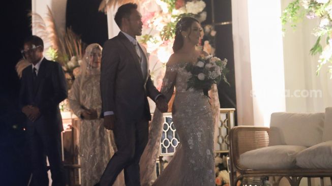 Pedangdut Jenita Janet dan suaminya, Danu Sofwan berjalan menuju panggung saat resepsi pernikahan mereka di Green Forest Resort, Bandung, Jawa Barat, Rabu (11/11). [Suara.com/Alfian Winanto]