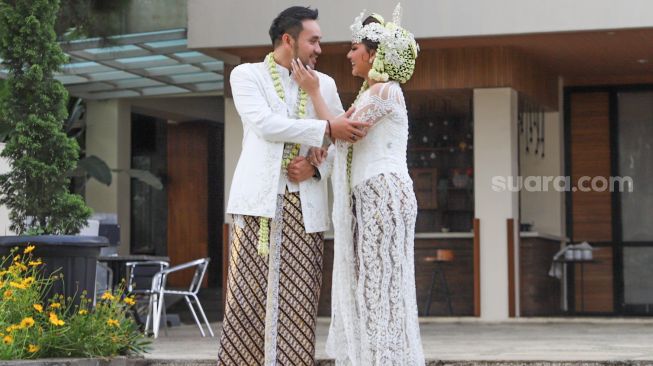 Pedangdut Jenita Janet dan suaminya, Danu Sofwan berpose didepan kamera usai melangsungkan pernikahan di Green Forest Resort, Bandung, Jawa Barat, Rabu (11/11). [Suara.com/Alfian Winanto]