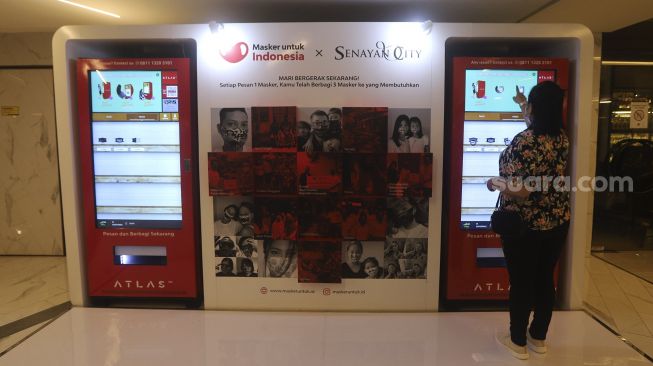 Pengunjung memilih masker yang dijual pada "vending machine" di Senayan City Mall, Jakarta, Rabu (11/11/2020). [Suara.com/Angga Budhiyanto]