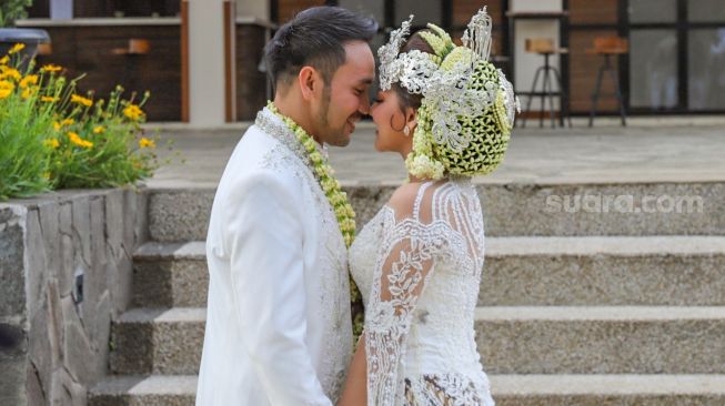 Pedangdut Jenita Janet dan suaminya, Danu Sofwan berpose mesra didepan kamera usai melangsungkan pernikahan di Green Forest Resort, Bandung, Jawa Barat, Rabu (11/11). [Suara.com/Alfian Winanto]
