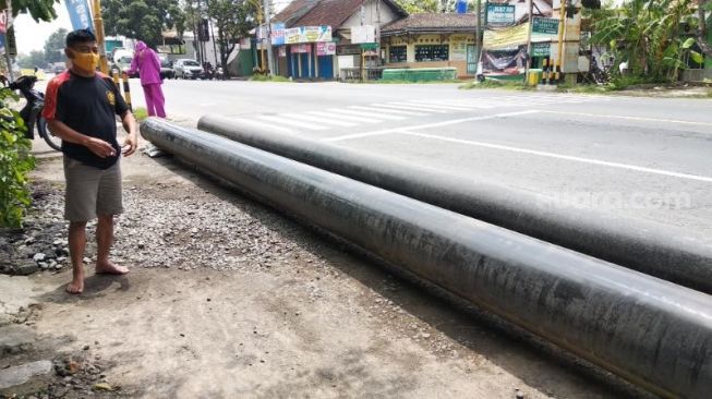 Warga Kalakan RT 3, Sutaryono, menunjukkan pipa dengan panjang 10 meter milik PT Pertamina yang tergeletak di depan halaman rumahnya, Desa Argorejo, Kecamatan Sedayu, Kabupaten Bantul, Kamis (12/11/2020). - (SuaraJogja.id/Muhammad Ilham Baktora)