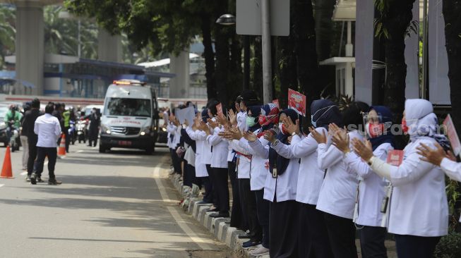 Sejumlah karyawan Kementerian Kesehatan melakukan tepuk tangan secara bersama di depan Gedung Kementerian Kesehatan Republik Indonesia, Jakarta, Kamis (12/11/2020). [Suara.com/Angga Budhiyanto]