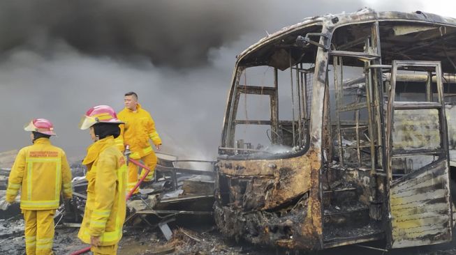 Personel Damkar Kabupaten Bogor melakukan pendinginan sejumlah bus Transjakarta bekas yang terbakar di Dramaga, Kabupaten Bogor, Jawa Barat, Jumat (13/11/2020). [ANTARA FOTO/Cepi Kurniawan]