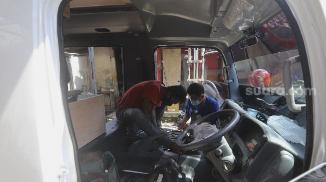 Pekerja menyelesaikan modifikasi mobil campervan di Bengkel Impro Campervan, Depok, Jawa Barat, Jumat (13/11/2020). [Suara.com/Angga Budhiyanto]