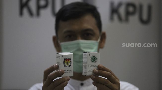 Petugas menunjukkan tinta di Gudang Logistik KPU, Depok, Jawa Barat, Jumat (13/11/2020). [Suara.com/Angga Budhiyanto]