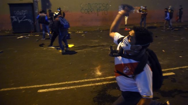 Demonstran melempari batu ke Polsi saat melakukan aksi terkait pemakzulan Presiden Martin Vizcarra di Lima, Peru, Kamis (12/11/2020).  [ERNESTO BENAVIDES / AFP]