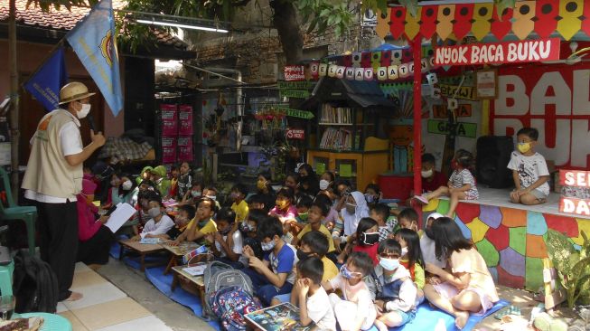 Pendongeng Adi Pamungkas (kiri) saat mendongeng di hadapan anak-anak warga Cakung Barat, Jakarta Timur, Sabtu (14/11/2020). [ANTARA FOTO/Suwandy]