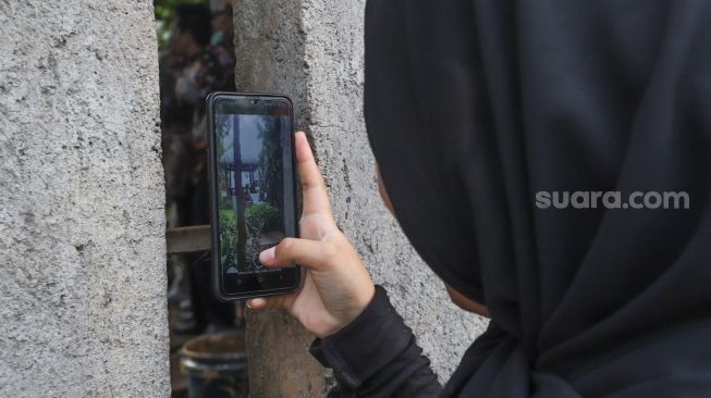 Warga mengabadikan momen pernikahan Komedian Sule dengan Nathalie Holscher dari sela - sela dinding di Jatisampurna, Bekasi, Jawa Barat, Minggu (15/11). [Suara.com/Alfian Winanto] 