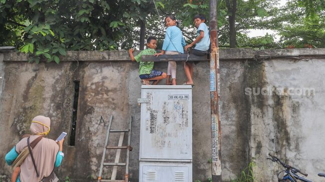 Warga memanjat dinding untuk melihat momen pernikahan Komedian Sule dengan Nathalie Holscher di Jatisampurna, Bekasi, Jawa Barat, Minggu (15/11). [Suara.com/Alfian Winanto] 