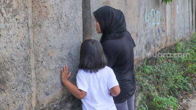 Warga menonton momen pernikahan Komedian Sule dengan Nathalie Holscher dari sela - sela dinding di Jatisampurna, Bekasi, Jawa Barat, Minggu (15/11). [Suara.com/Alfian Winanto] 