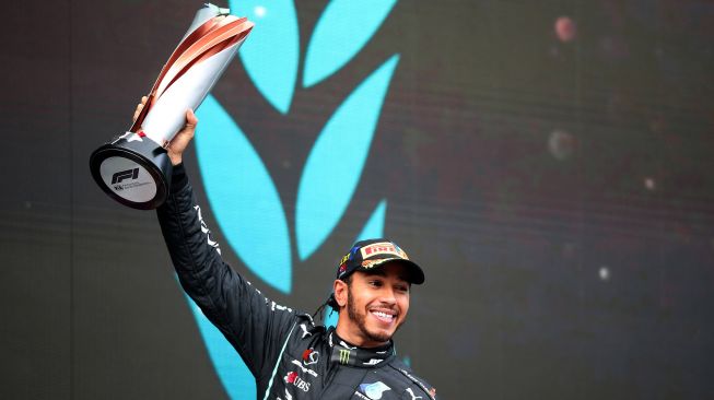 Pebalap Mercedes Lewis Hamilton mengangkat trofi di podium usai memenangi balapan F1 Grand Prix Turki di Istanbul, Minggu (15/11/2020). [TOLGA BOZOGLU / POOL / AFP]