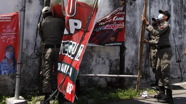 Petugas Satpol PP Solo menertibkan Alat Peraga Kampanye (APK) Pilkada 2020 di Pasar Kliwon, Solo, Jawa Tengah, Selasa (17/11/2020). [ANTARA FOTO/Maulana Surya]