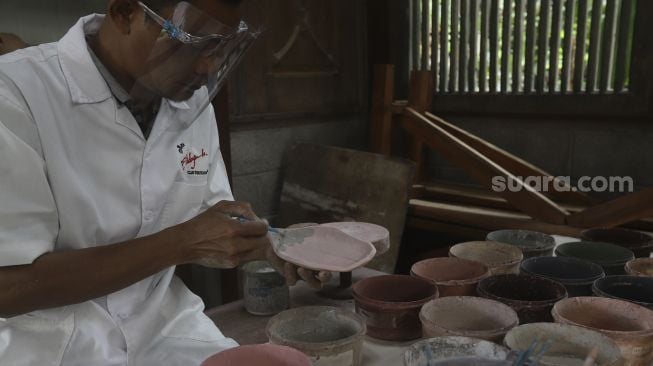 Pekerja menyelesaikan produksi keramik hias di Studio Workshop Rumah Keramik F Widayanto, Tanah Baru, Beji, Kota Depok, Jawa Barat, Rabu (18/11/2020). [Suara.com/Angga Budhiyanto]