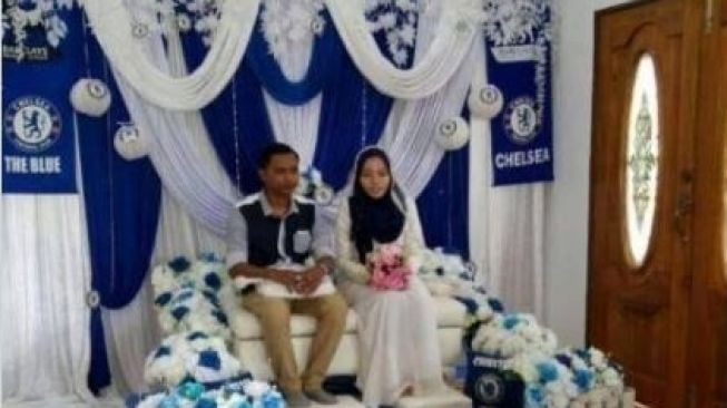 Pasangan penganting nikah pakai atribut Chelsea. (Twitter.com/alexasaffira)