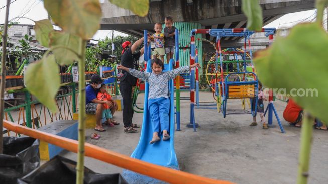 Anak - anak bermain wahana perosotan di Taman Bermain yang ada di Kolong Jalan Layang Rawajati, Jakarta Selatan, Kamis (19/11). [Suara.com/Alfian Winanto]