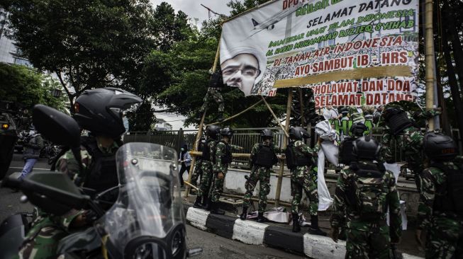 Prajurit TNI menurunkan spanduk bergambar Habib Rizieq Shihab saat patroli keamanan di Petamburan, Jakarta, Jumat (20/11/2020).  [ANTARA FOTO/Aprillio Akbar]