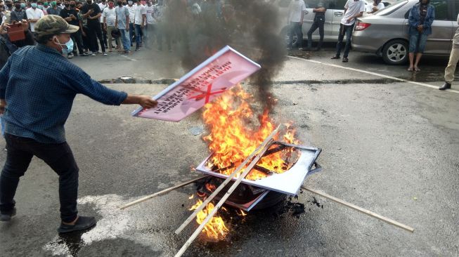 Massa membakar spanduk bergambar Habib Rizieq di Medan. (Suara.com/Muhlis)