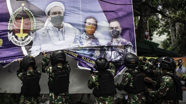 Prajurit TNI menurunkan spanduk bergambar Habib Rizieq Shihab saat patroli keamanan di Petamburan, Jakarta, Jumat (20/11/2020).  [ANTARA FOTO/Aprillio Akbar]