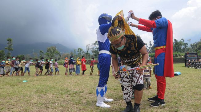 Seorang relawan menggunakan kostum super hero saat bermain bersama anak-anak di Tempat Pengungsian Sementara Gunung Merapi, Klakah, Selo, Boyolali, Jawa Tengah, Sabtu (21/11/2020).  [ANTARA FOTO/Aloysius Jarot Nugroho]
