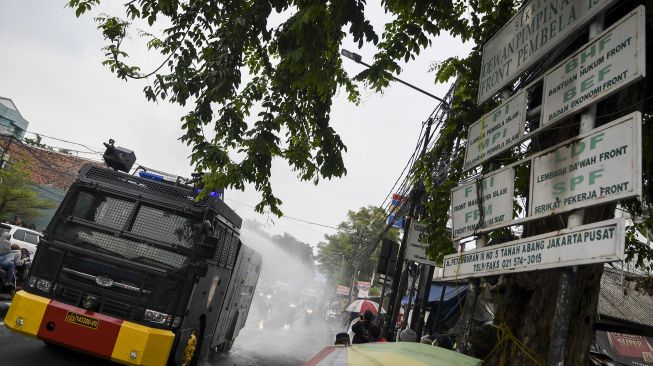 Sebuah kendaraan meriam air (water canon) menyemprotkan cairan disinfektan di kawasan Petamburan, Jakarta Pusat, Minggu (22/11/2020). [ANTARA FOTO/M Risyal Hidayat]