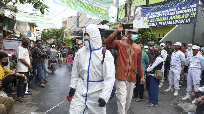 Anggota kepolisian dengan mengenakan hazmat menyemprotkan cairan disinfektan di kawasan Petamburan III, Jakarta Pusat, Minggu (22/11/2020). [ANTARA FOTO/M Risyal Hidayat]