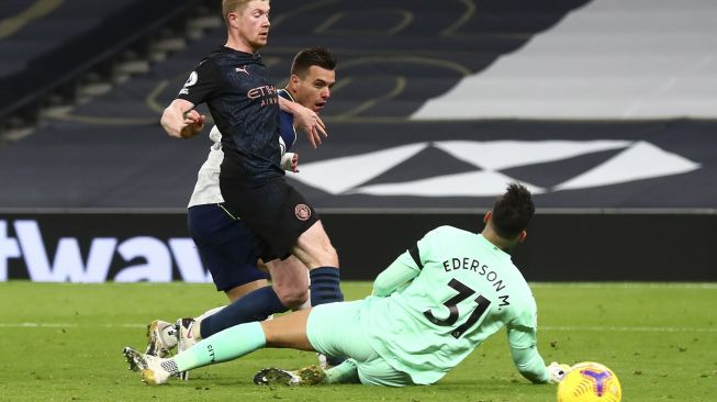 Gelandang Tottenham Hotspur Giovani Lo Celso (tengah) menendang bola melewati kiper Manchester City Ederson (kanan) untuk mencetak gol kedua mereka selama pertandingan sepak bola Liga Premier Inggris antara Tottenham Hotspur melawan Manchester City di Tottenham Hotspur Stadium, London, pada (21/11/2020). [Clive Rose / POOL / AFP]