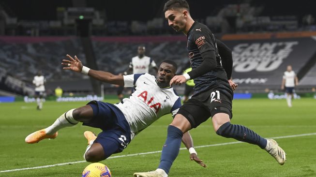 Bek Tottenham Hotspur Serge Aurier (kiri) berhadapan dengan gelandang Manchester City Ferran Torres (kanan) selama pertandingan sepak bola Liga Premier Inggris antara Tottenham Hotspur melawan Manchester City di Tottenham Hotspur Stadium, London, pada (21/11/2020). [NEIL HALL / POOL / AFP]