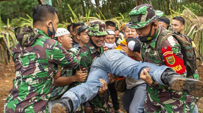 Prajurit TNI melakukan evakuasi secara paksa warga yang berada di sekitar area pertempuran saat Latihan Antar Kecabangan TNI AD Kartika Yudha Tahun 2020 di Desa Sepancar, Lawan Kulon, Baturaja Timur, Ogan Komering Ulu (OKU), Sumatera Selatan, Senin (23/11/2020). [ANTARA FOTO/Nova Wahyudi]