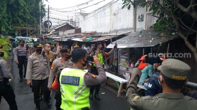 Aparat gabungan saat menyemprot disinfektan di sekitar rumah Habib Rizieq di Petamburan. (Suara.com/Bagaskara)