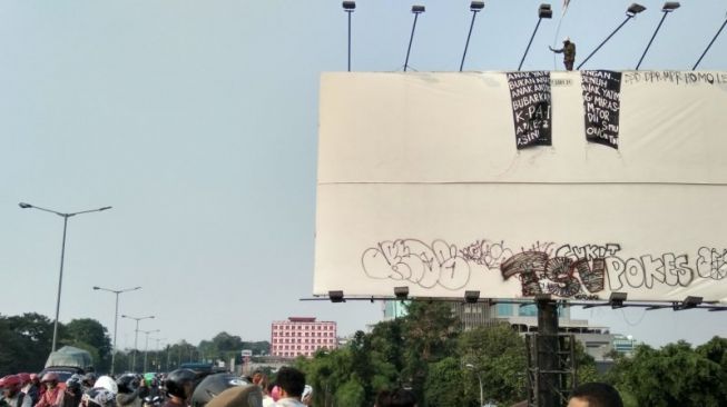 Agustinus Woro panjat papan reklame yang ada di jalan layang Raya Bogor, Pasar Rebo, Jakarta, saat aksi panjat tiang baliho, Rabu (12/9/2018) petang. [ANTARA/Ricky Prayoga]