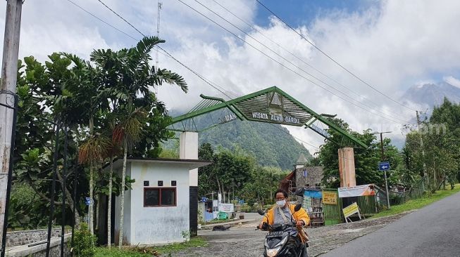 Warga melintasi jalanan dengan latar belakang Gunung Merapi di Kaliurang, Hargobinangun, Pakem, Sleman, Rabu (25/11/2020). - (SuaraJogja.id/Hiskia Andika)