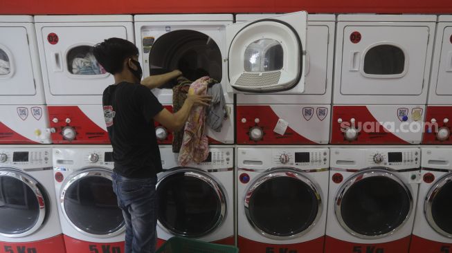 Pekerja membersihkan baju pelanggan di Jourdan Laundry Expert, Ampera Raya, Jakarta, Kamis (26/11/2020). [Suara.com/Angga Budhiyanto]