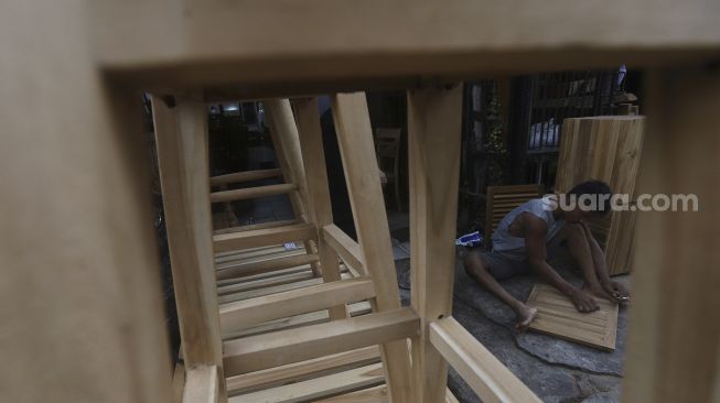 Pekerja menyelesaikan produksi mebel kayu di salah satu workshop furniture di kawasan Kemang, Jakarta, Kamis (26/11/2020). [Suara.com/Angga Budhiyanto]