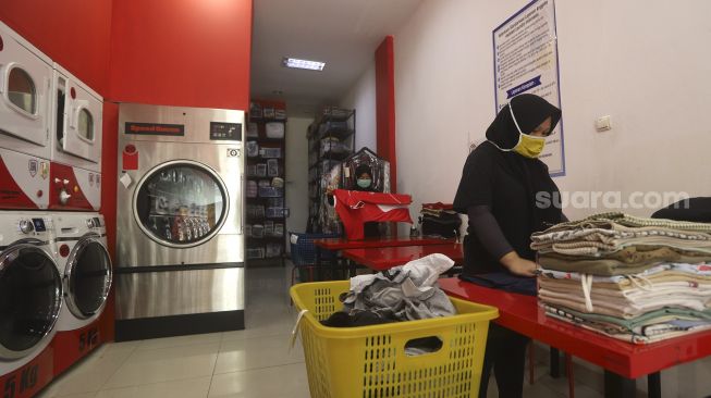 Pekerja melakukan pengemasan baju pelanggan sebagai tahapan akhir di Jourdan Laundry Expert, Ampera Raya, Jakarta, Kamis (26/11/2020). [Suara.com/Angga Budhiyanto]