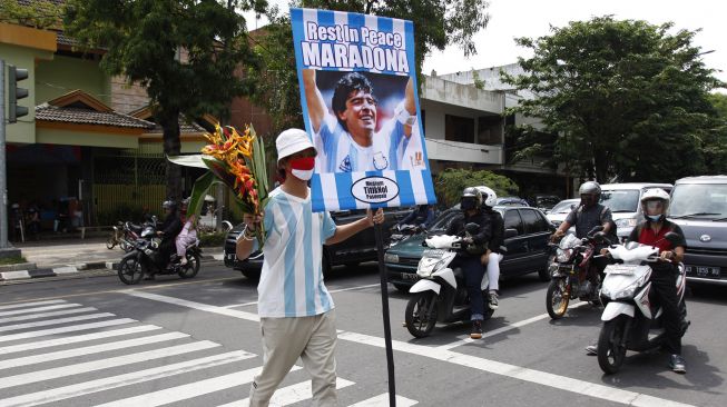 Suporter sepakbola Pasoepati mengusung poster ucapan duka cita untuk mengenang legenda sepakbola dunia Diego Maradona yang meninggal dunia saat aksi, di Solo, Jawa Tengah, Kamis (26/11/2020).  [ANTARA FOTO/Maulana Surya]
