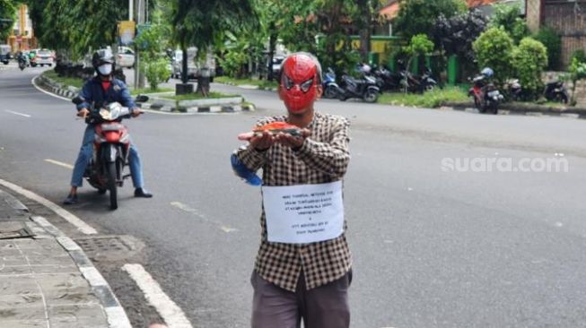 Aktivis Jogja Corruption Watch (JCW), Baharuddin Kamba, melakukan aksi tunggal di depan pintu gerbang Stadion Mandala Krida Yogyakarta pada Kamis (26/11/2020). - (SuaraJogja.id/Hiskia Andika)