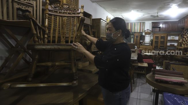 Pemilik usaha mebel kayu merapikan produk mebel yang dipajang di salah satu workshop furniture di kawasan Kemang, Jakarta, Kamis (26/11/2020). [Suara.com/Angga Budhiyanto]