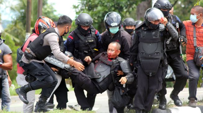 Anggota polisi yang terluka dievakuasi unjuk rasa di Kota Sorong, Papua Barat, Jumat (27/11/2020). [ANTARA FOTO/Olha Mulalind]
