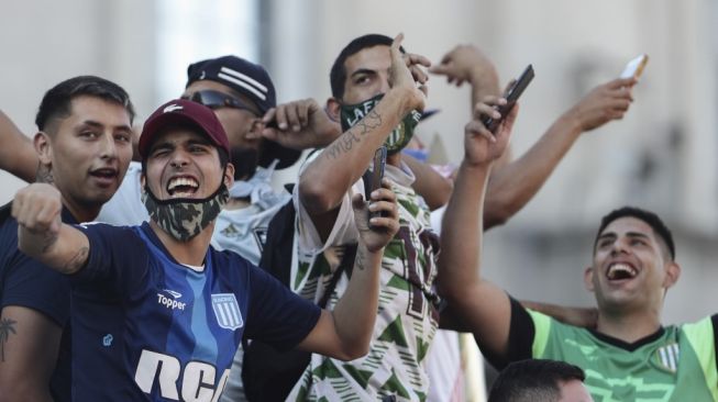 Fans bersorak saat iring-iringan pemakaman mendiang legenda sepak bola Argentina Diego Armando Maradona meninggalkan Istana Presiden di Casa Roseda menuju pemakaman di Jardin Bella Vista, di provinsi Buenos Aires, pada Kamis (26/11/2020) waktu setempat. [Alejandro PAGNI / AFP]