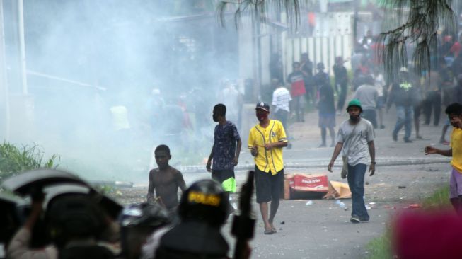 Massa berjalan melintasi asap yang mengepul saat unjuk rasa di Kota Sorong, Papua Barat, Jumat (27/11/2020). ANTARA FOTO/Olha Mulalinda