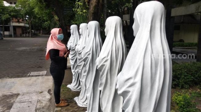 Seorang mahasiswi ISI Yogayakarta melintasi jejeran patung putih berbentuk wanita berkerudung di Kampus ISI Yogyakarta, Jumat (27/11/2020). - (SuaraJogja.id/Muhammad Ilham Baktora)