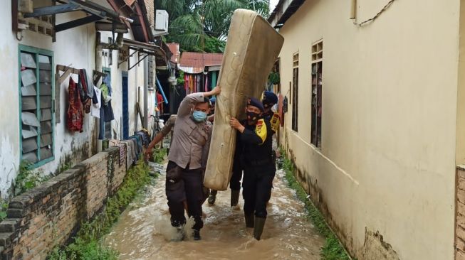 Personel Brimob Batalyon B Pelopor Tebing Tinggi melakukan evakuasi barang-barang korban banjir. [Foto: Istimewa]