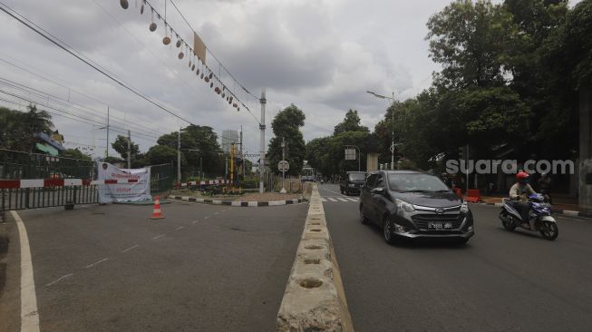 Sejumlah kendaraan bermotor melintas di samping perlintasan sebidang yang sudah ditutup di kawasan Stasiun Palmerah, Jakarta, Minggu (29/11/2020). [Suara.com/Angga Budhiyanto]