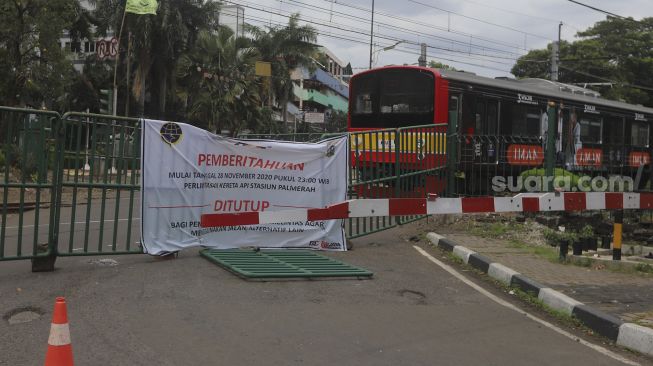 Rangkaian Kereta Rel Listrik (KRL) Comutter Line melintas pada perlintasan sebidang yang sudah ditutup di kawasan Stasiun Palmerah, Jakarta, Minggu (29/11/2020). [Suara.com/Angga Budhiyanto]