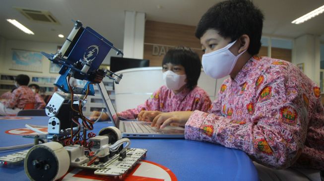 Murid SD Muhammadiyah 4 Surabaya Octavian Dwiki Sucahyo (kanan) dan M Azka Dzakwan (kedua kanan) memprogram robot transporter buatan mereka untuk diuji coba, di Surabaya, Jawa Timur, Senin (30/11/2020). ANTARA FOTO/Moch Asim