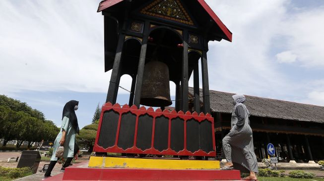 Wisatawan melihat peninggalan sejarah lonceng cakra donya, di halaman museum Aceh, Banda Aceh, Aceh, Senin (30/11/2020).  ANTARA FOTO/Irwansyah Putra]