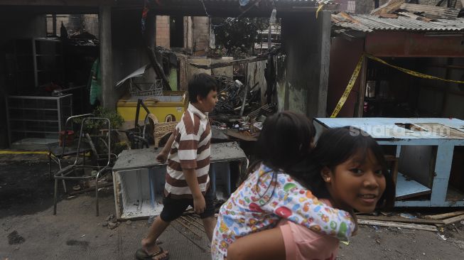 Sejumlah anak melintas di depan rumah yang terbakar di Petamburan, Jakarta, Senin (30/11/2020). [Suara.com/Angga Budhiyanto]