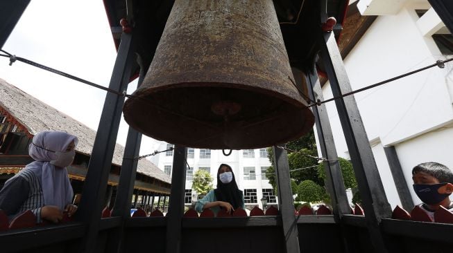 Wisatawan melihat peninggalan sejarah lonceng cakra donya, di halaman museum Aceh, Banda Aceh, Aceh, Senin (30/11/2020).  ANTARA FOTO/Irwansyah Putra]