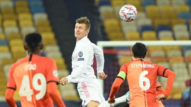 Gelandang Real Madrid Toni Kross menyundul bola saat timnya menghadapi Shakhtar Donetsk di matchday kelima Grup B Liga Champions, di Olimpiyskiy Stadium, Rabu (2/12/2020) dini hari WIB. [Sergei SUPINSKY / AFP]