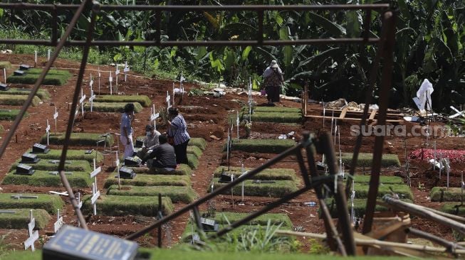 Warga berziarah ke makam keluarganya yang meninggal akibat COVID-19 di TPU Pondok Ranggon, Jakarta, Rabu (2/12/2020). [Suara.com/Angga Budhiyanto]